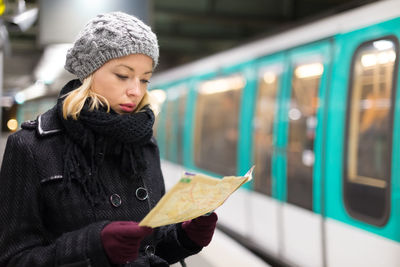 Young woman holding umbrella in train during winter