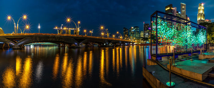 Illuminated bridge over river against sky at night