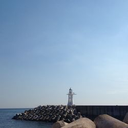 Lighthouse on beach against clear sky
