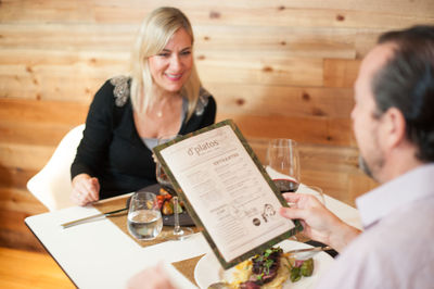 Man holding menu while having food with woman in restaurant