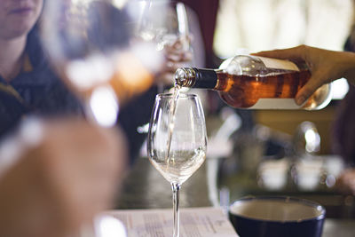 Midsection of man pouring wine in glass on table