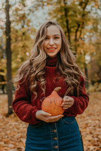 Portrait of smiling young woman standing during autumn