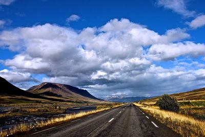 Country road against cloudy sky