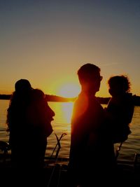 Silhouette people on beach against clear sky during sunset