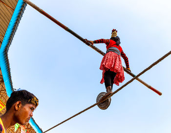 Low angle view of man holding rope against clear sky