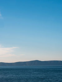 Scenic view of sea and mountains against clear blue sky