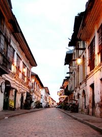 Street amidst illuminated city against sky