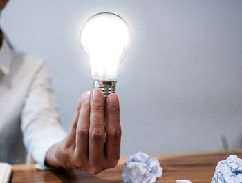 Close-up of hand holding illuminated light bulb