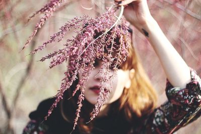 Close-up of woman with pink flowers against blurred background