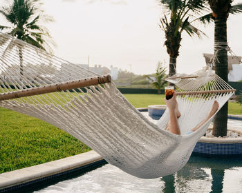 Man relaxing on hammock by swimming pool