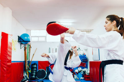 Two young women practice taekwondo in a training center