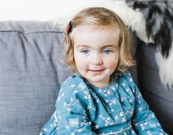 Smiling cute girl sitting on sofa at home