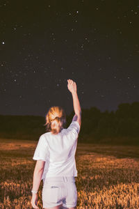 Rear view of woman standing on land against sky at night