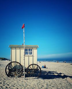 Lifeguard hut on beach against clear blue sky