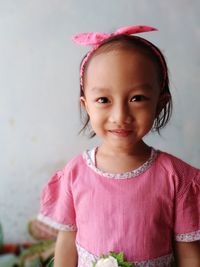 Portrait of smiling girl standing against pink wall