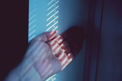 Close-up of sunlight falling on woman by wall