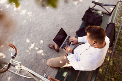 High angle view of businessman using laptop while sitting on park bench