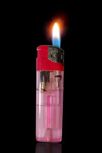 Close-up of burning candle against black background