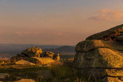 Rock formations on landscape against sky during sunset