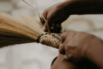 Close-up of person working on handcrafted walis tambo or brooms