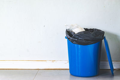 Garbage bin on floor against wall