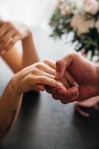 Cropped couple holding hands on table