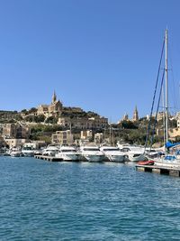 Boats in sea against clear blue sky