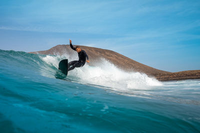 Man surfing on sea against sky