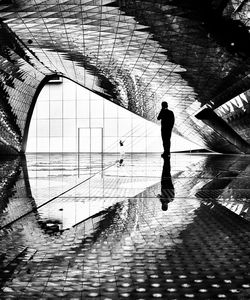 Rear view of silhouette man walking on tiled floor