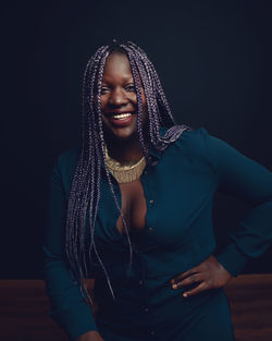 Portrait of smiling young woman against black background