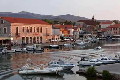 Boats moored at harbor against buildings in city