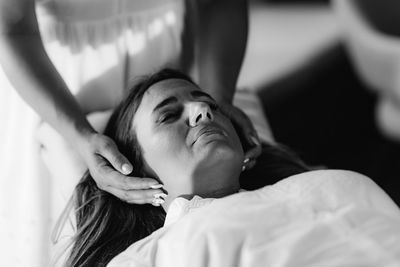 Reiki therapist transferring energy. peaceful woman lying with her eyes closed.