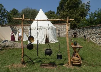 Wooden stand with old pans and pots in front of a historical tent at a historical market