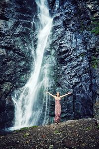 Woman standing by waterfall