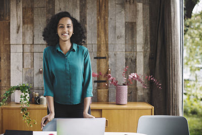 Portrait of smiling businesswoman standing against wood paneling in portable office truck