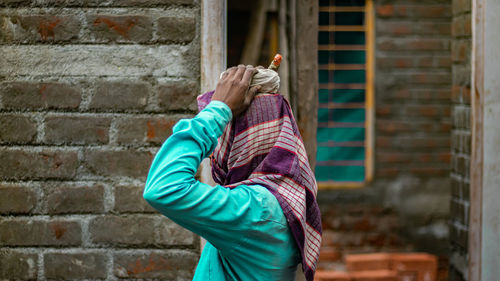 Side view of woman standing against the brick walls.