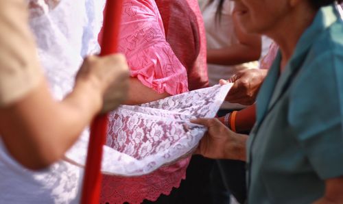 Midsection of people holding paper