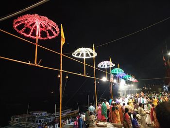 People in amusement park against sky at night