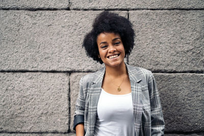 Portrait of smiling young woman against wall