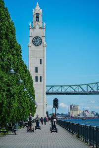 People on bridge against blue sky