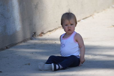 Portrait of boy sitting on concrete footpath