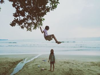 Rear view of woman jumping at beach