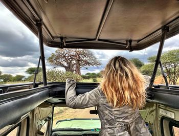 Rear view of woman standing in jeep