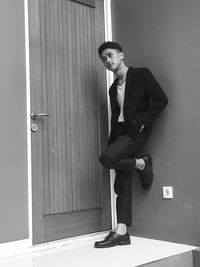 Full length of young man standing by door