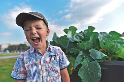 Boy shouting while standing by plants on field