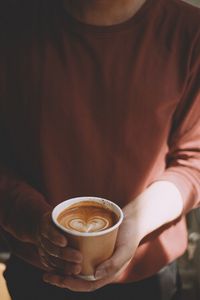 Midsection of man holding coffee cup