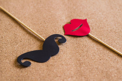 High angle view of artificial mustache and lips on cardboard