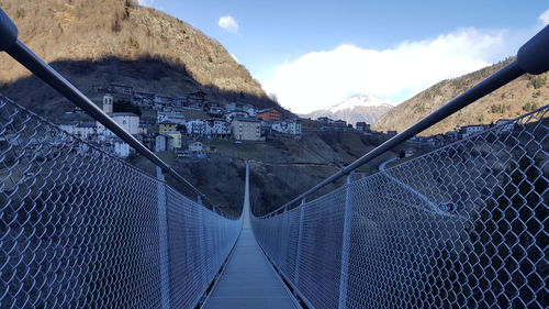 Panoramic shot of footbridge amidst buildings against sky