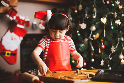 Girl preparing cookies on table during christmas