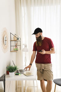 Bearded editor using laptop computer while standing at home